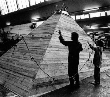 Behngen einer Holzpyramide in einer Fabrikhalle mit einer Lichterkette